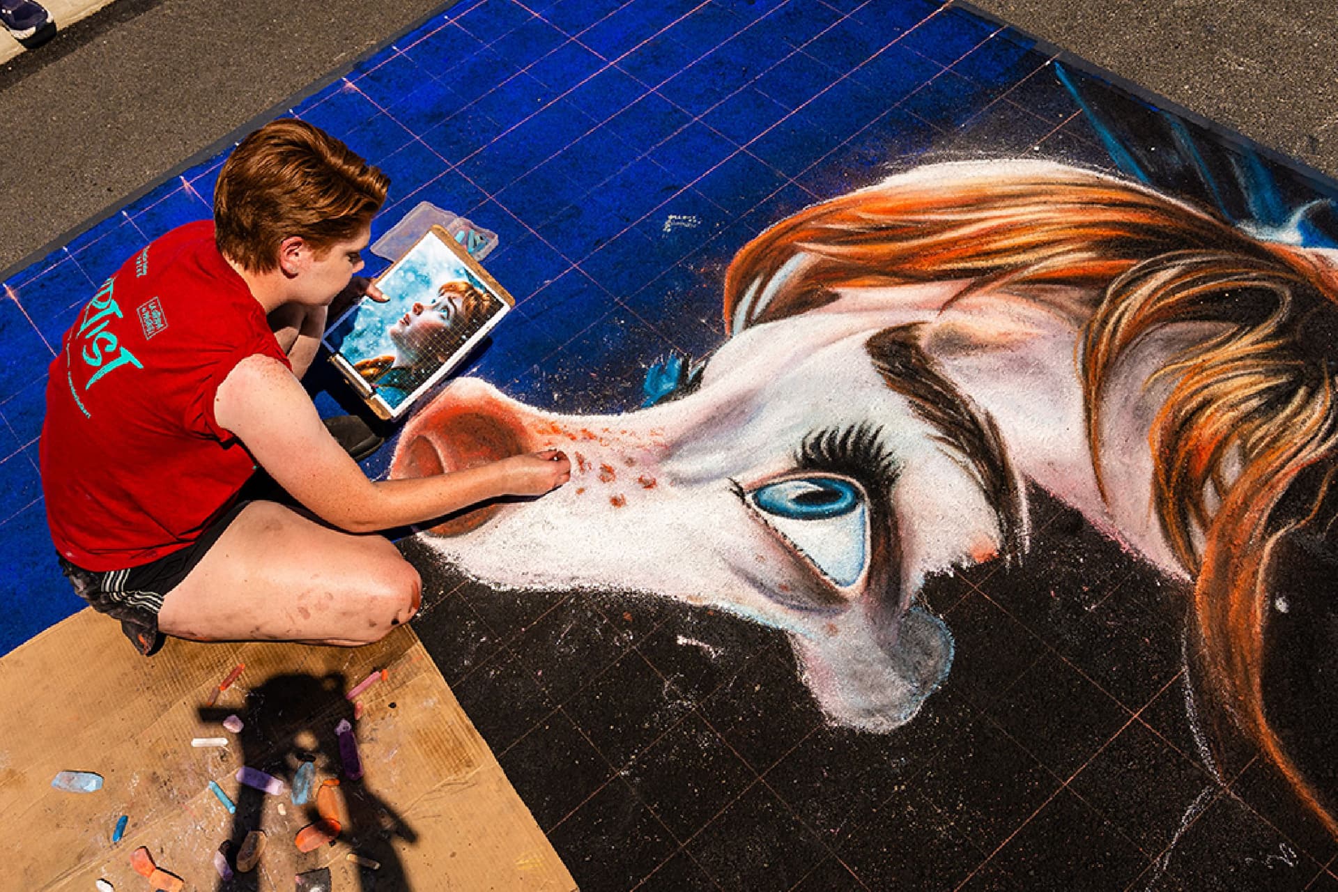 A chalk artist creates a hyper-photorealistic chalk portrait.